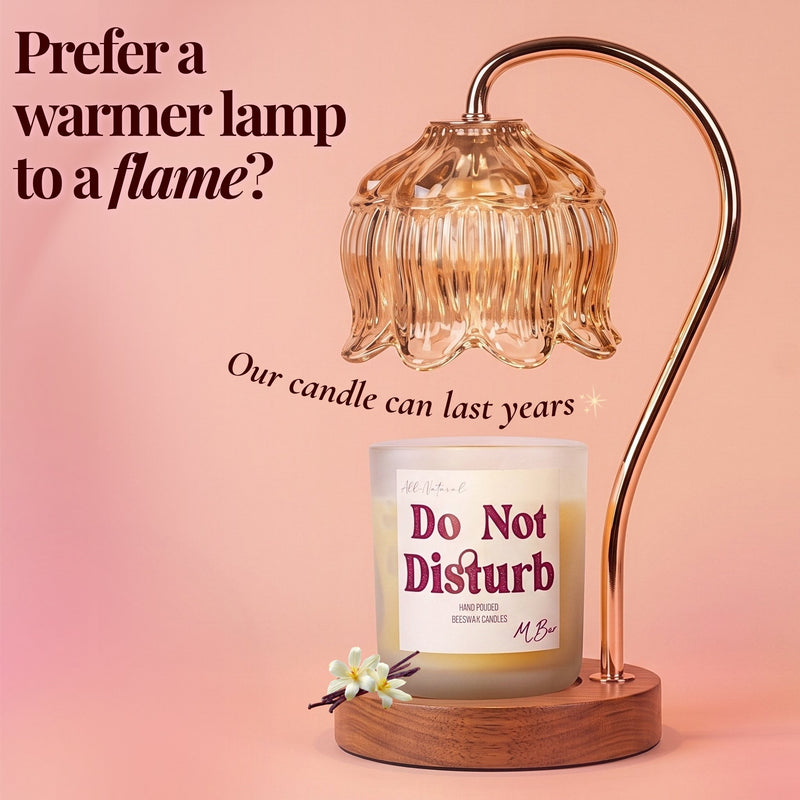 A lit amber glass bell-shaped lamp with a curved metallic arm and wooden base sits above a candle jar labeled 'Do Not Disturb' on a soft pink background with decorative text.