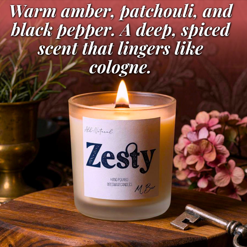 Lit Zesty beeswax candle with wooden wick beside flowers and key