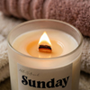 Lit cream Sunday Reset beeswax candle with wooden wick and flame