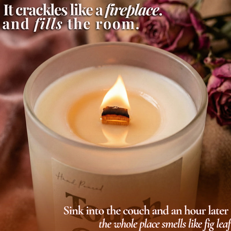 Lit beeswax candle with crackling wooden wick beside pink roses