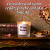 Lit Wine Down beeswax candle on antique table with cinnamon and books