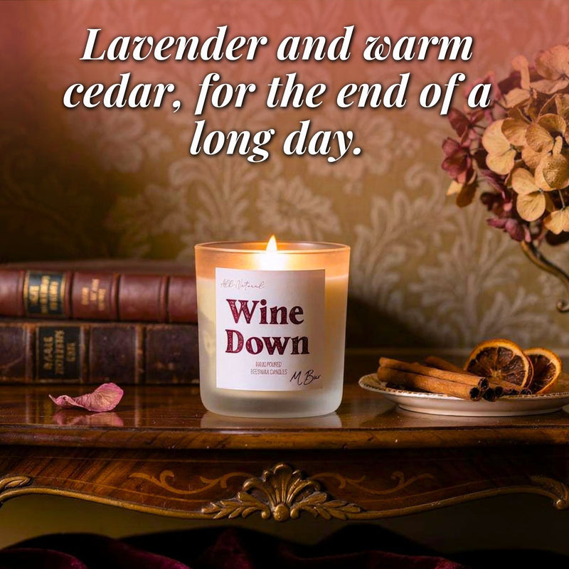 Lit Wine Down beeswax candle on antique table with cinnamon and books