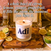 Lit Adi beeswax candle with wooden wick among sliced citrus