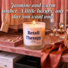 Lit Retail Therapy beeswax candle on vanity with perfume and jewelry